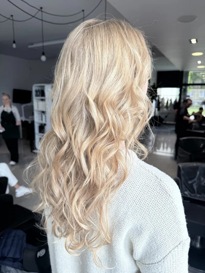 Jasne blond loki z miękkim przejściem od nasady, widok z tyłu w salonie