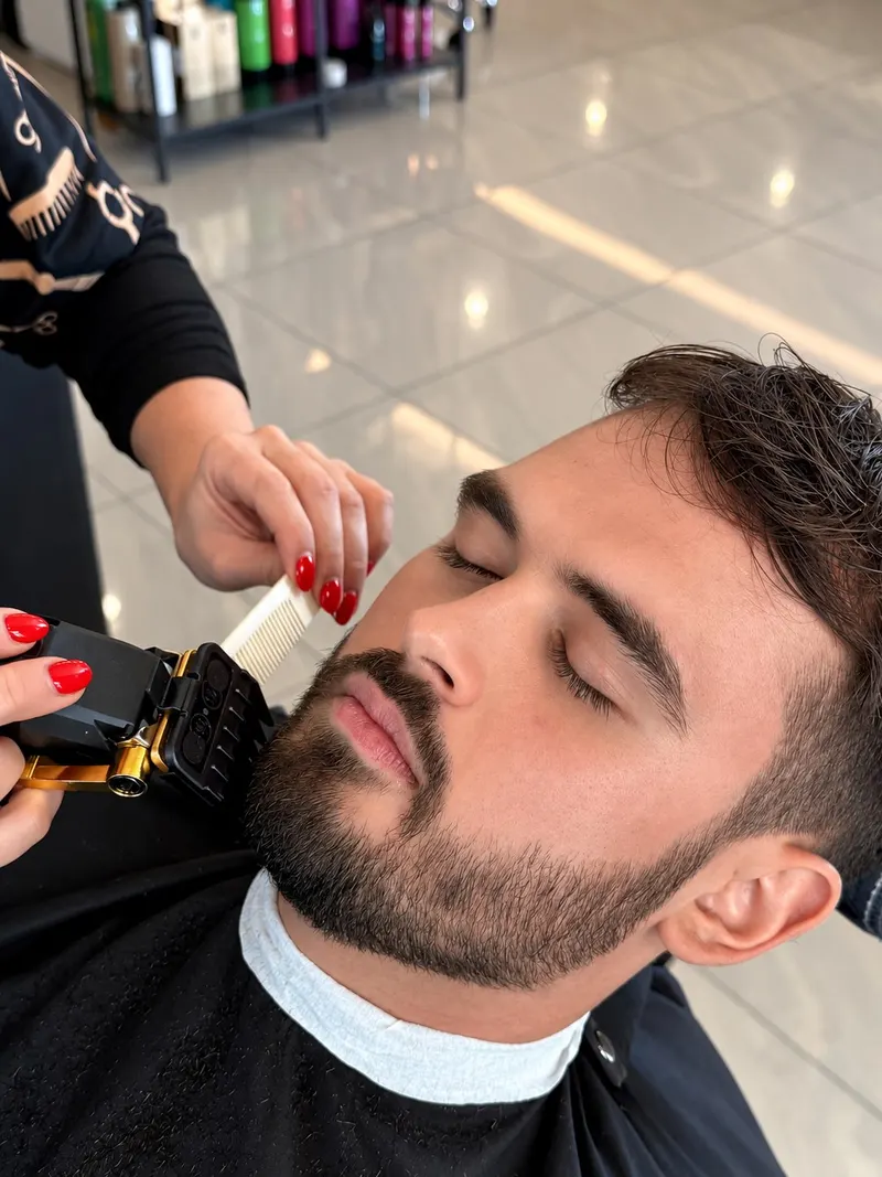 Barberka konturuje brodę klienta trymerem